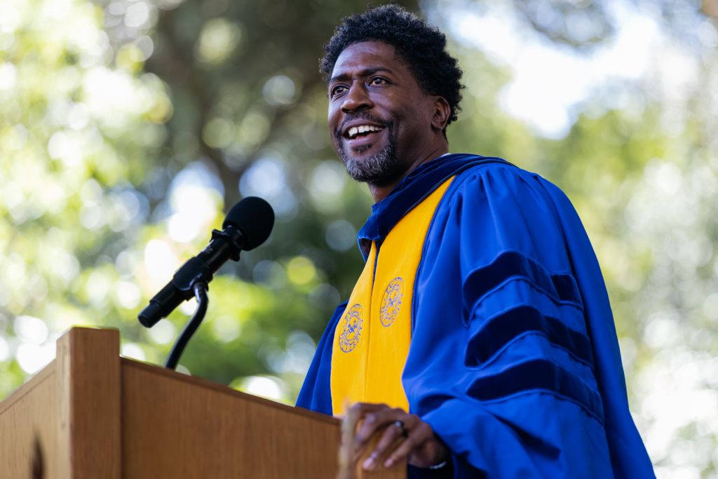 Open video Lerone Martine speaks at a podium during Baccalaureate with blurred greenery in the background. in a modal