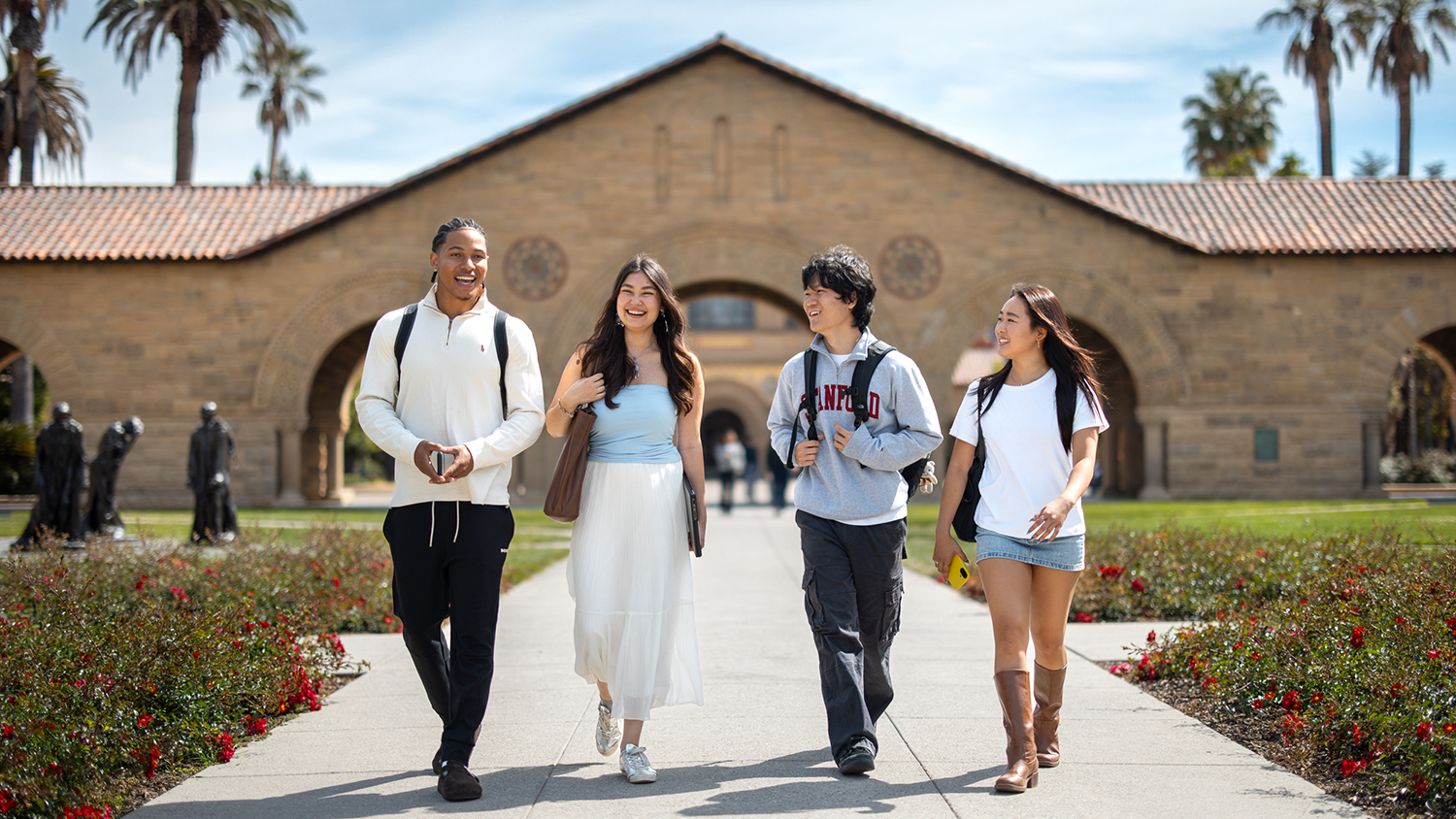 Four students walking together through the Main Quad on the Stanford campus.