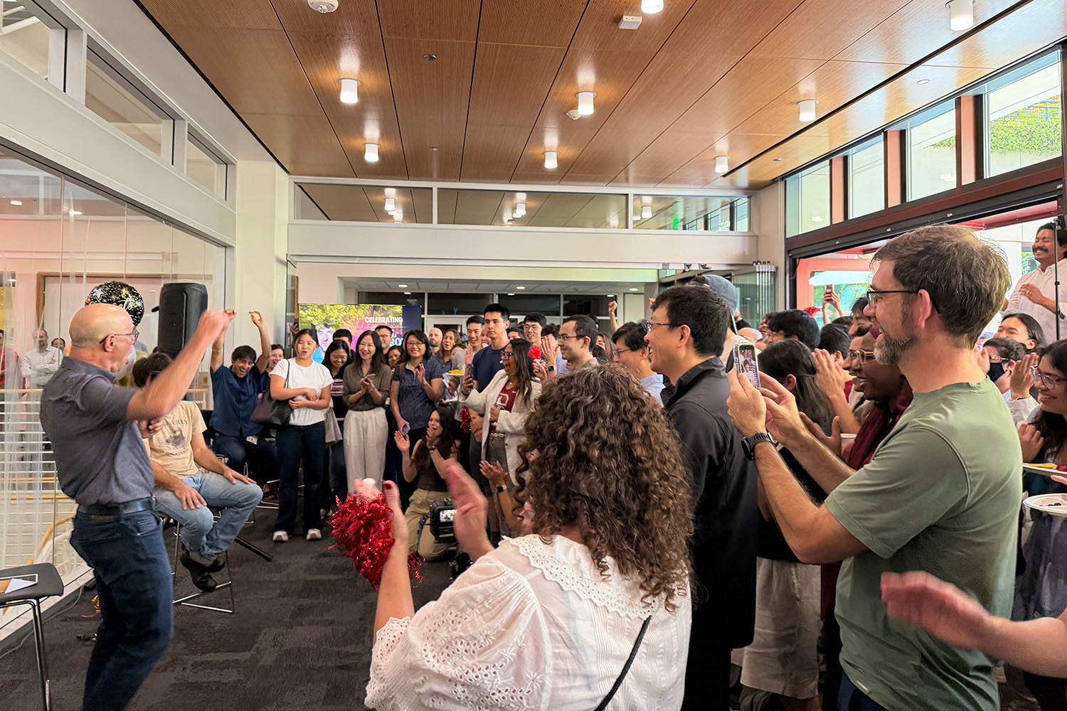 A crowd claps and films on phones in celebration of Karl Deisseroth.