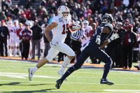 Stanford football player rinning with the ball with an opponent tries to head him off.