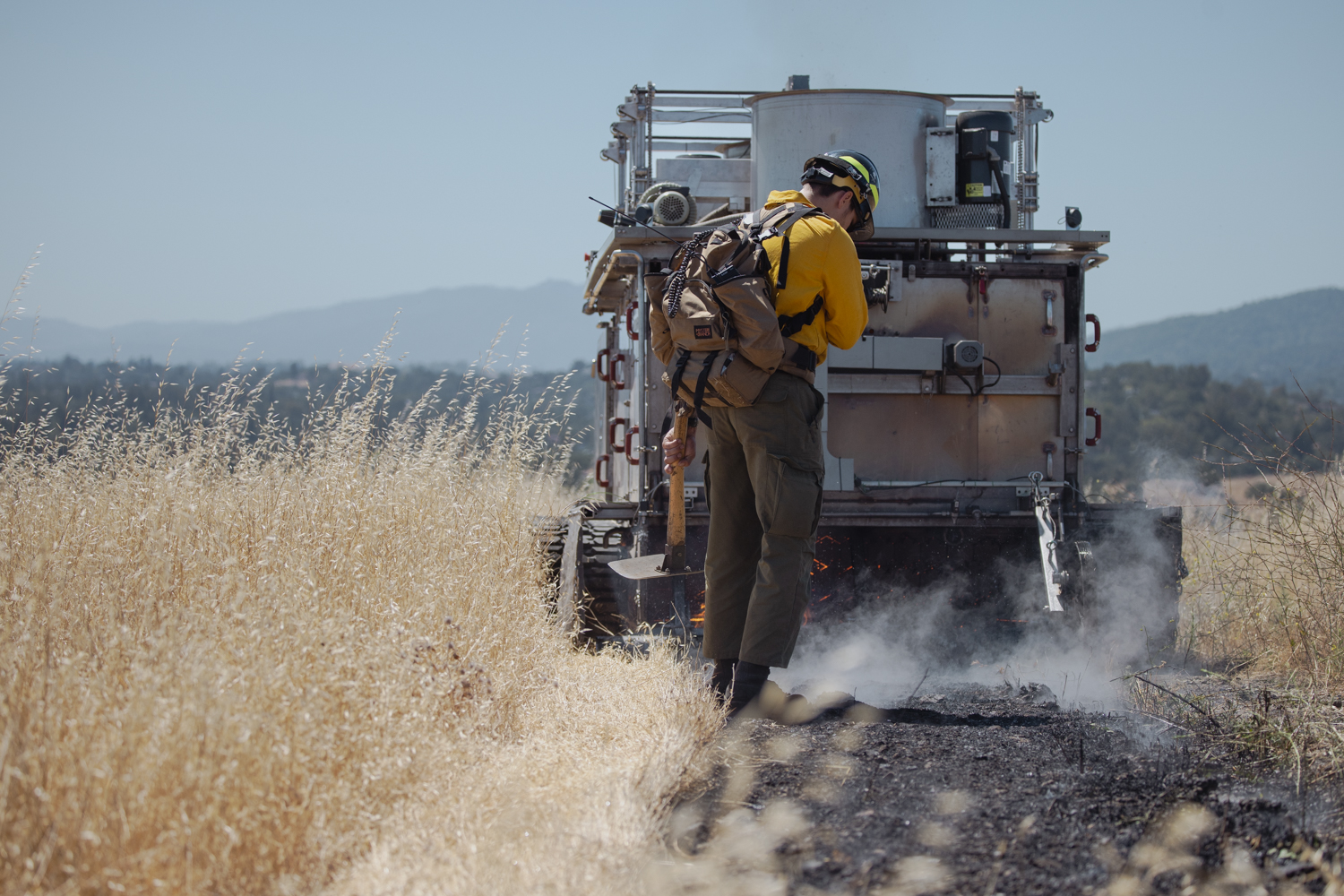 A team member follows behind BurnBot with a handheld hoe.