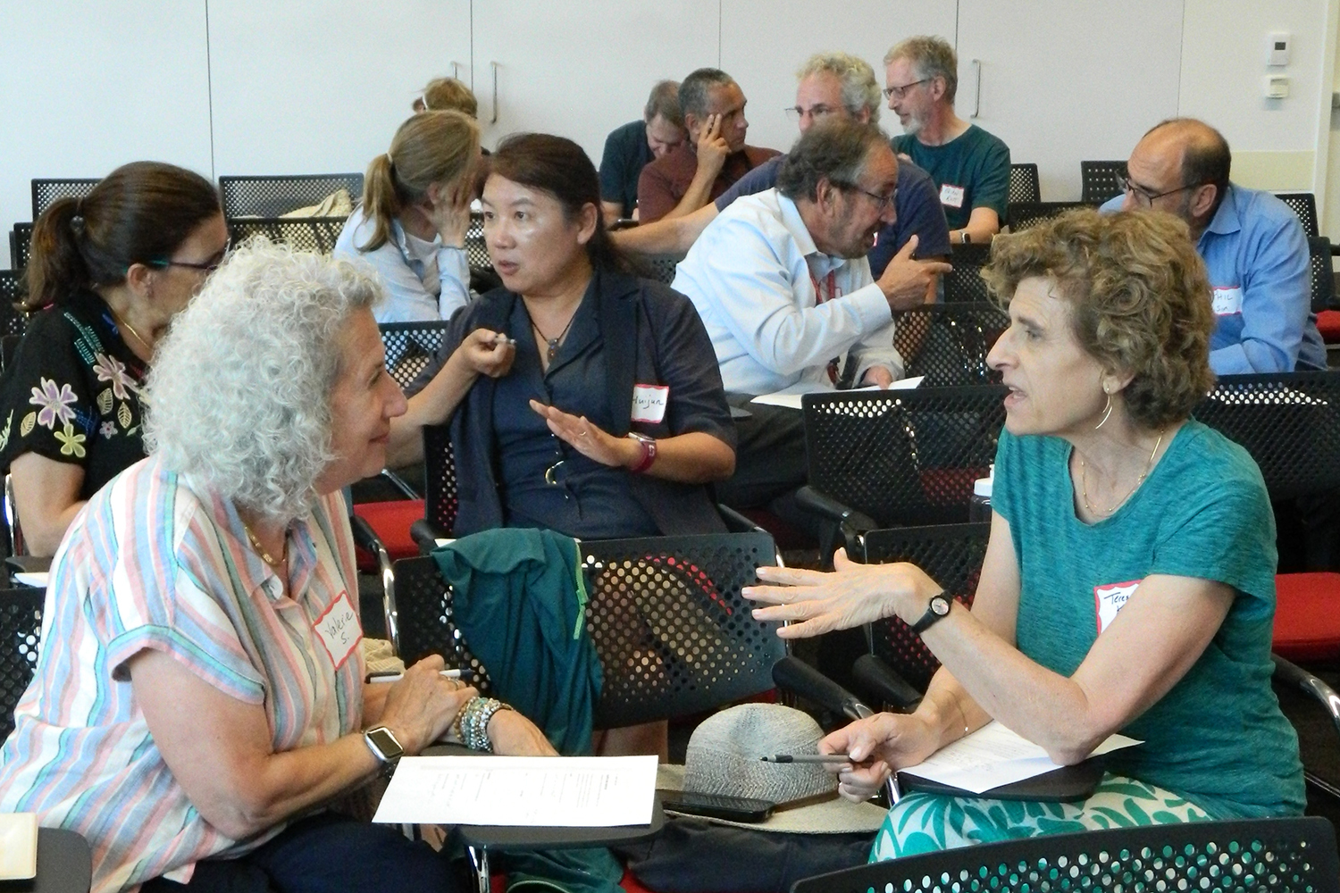 Members of the Senior Academy at Stanford Medicine sit in a classroom and have conversations with each other.