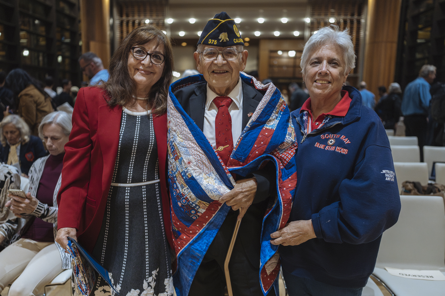 U.S. Marine Corps veteran Manny Velasco is draped in a red, white, and blue quilt of valor, presented by members of the South Bay Blue Star Moms organization.