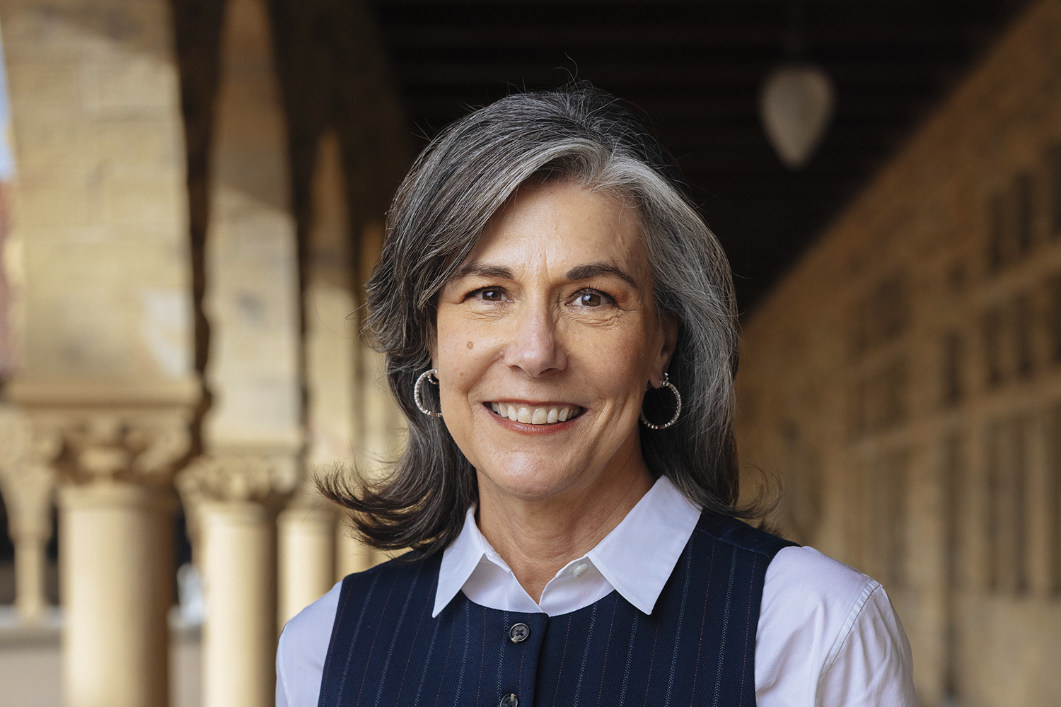 Whitney McNair posing for a photo under sandstone archways on the Stanford campus.