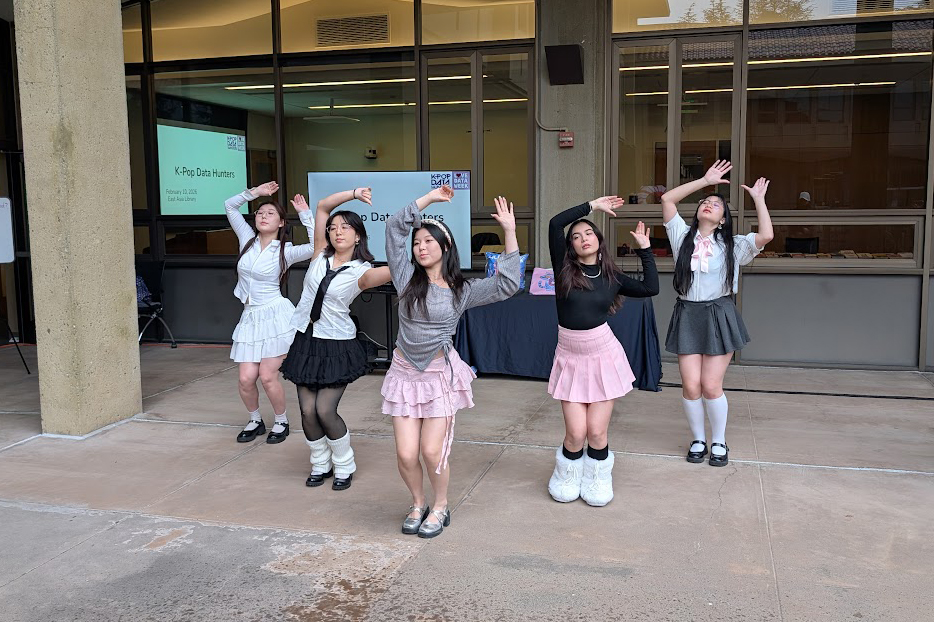 A group of dancers performs in matching outfits outside, promoting a K-Pop event with a banner indicating "K-Pop Data Hunters."