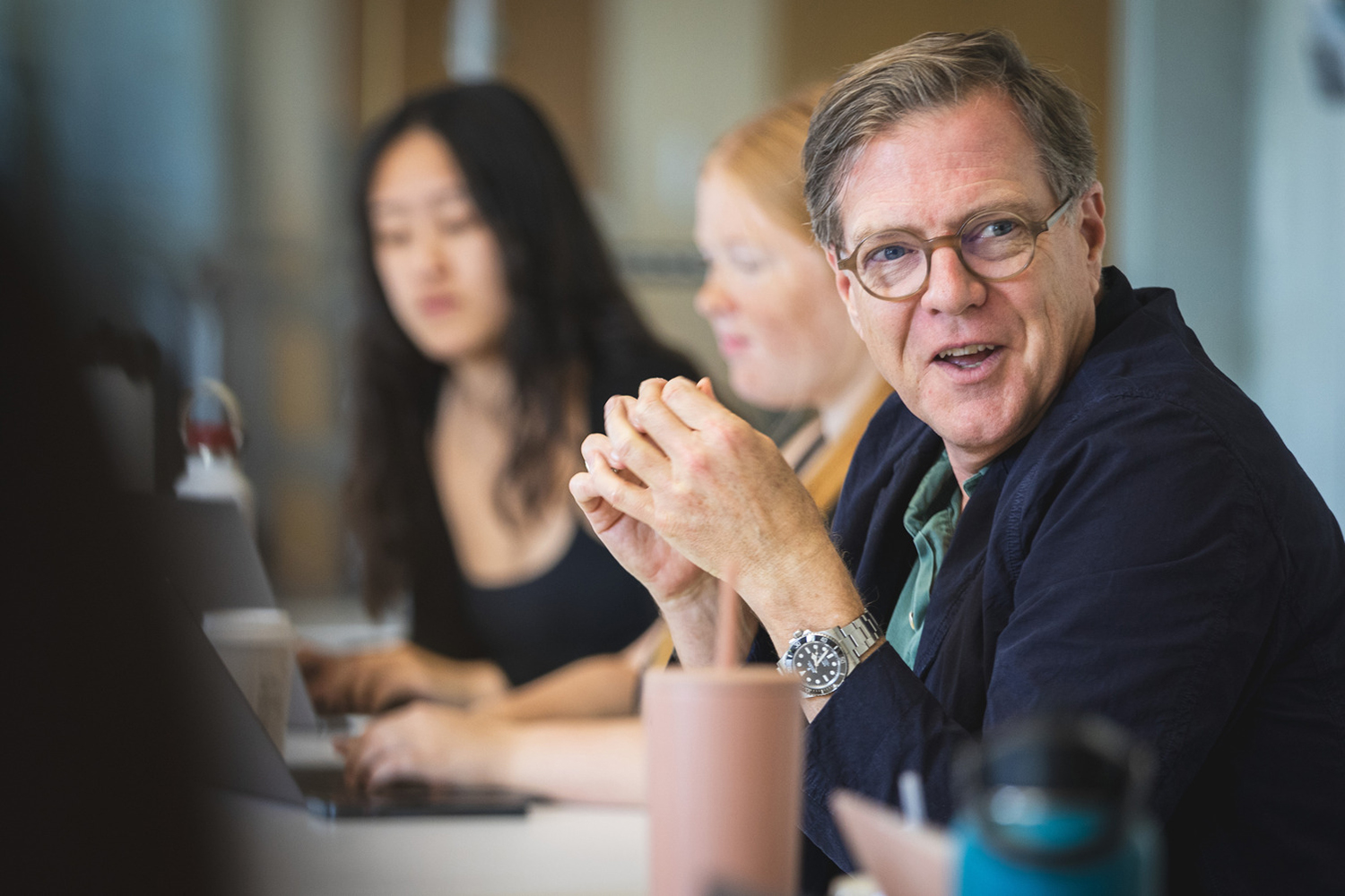 Mitchell Stevens sits at a table, looking toward the side to engage in a conversation.