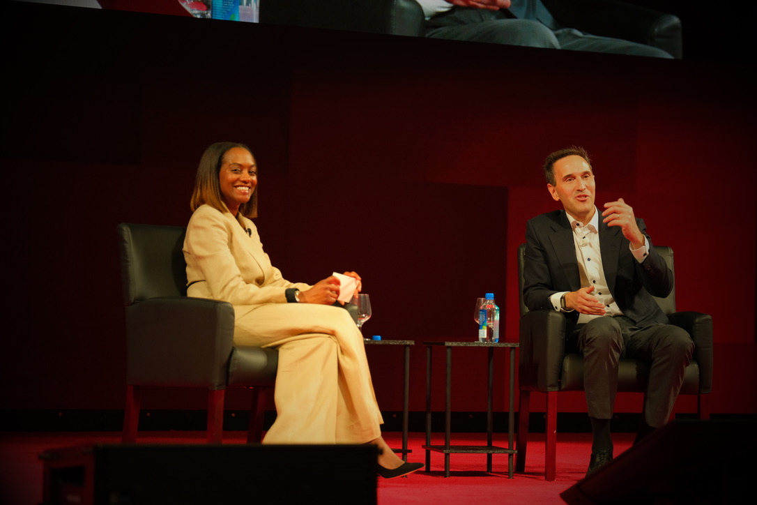 Nadia Rawlinson and Jonathan Levin sit in chairs on stage during a panel discussion with water bottles on a small table between them.