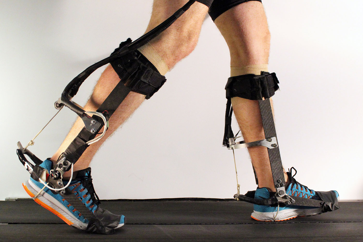 A person walking while wearing biomechanical exoskeletons on their legs to assist movement and enhance mobility.