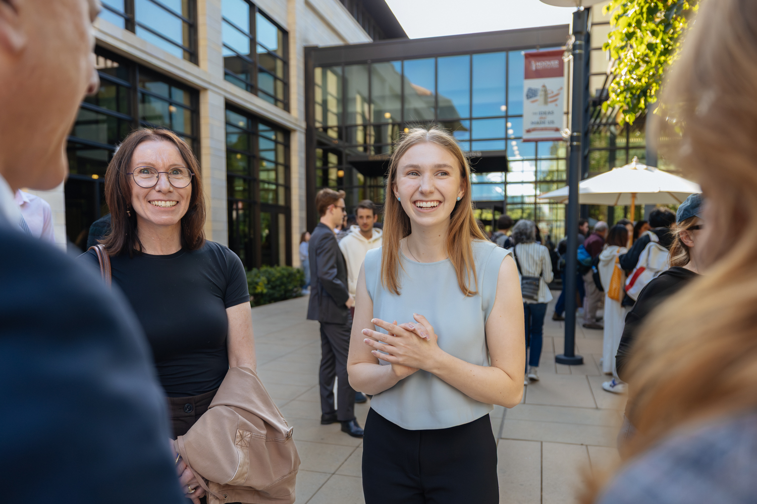 Colette Benko smiling while talking with a small group outside building.
