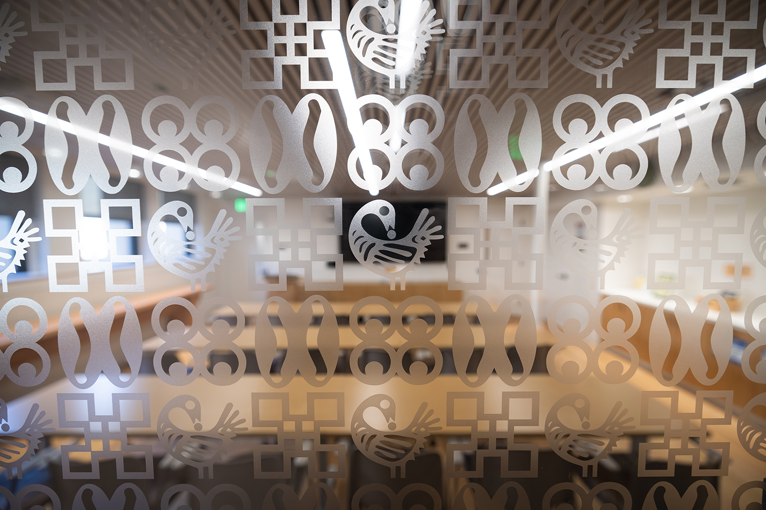 Frosted glass with repeating pattern of symbols from the Akan people of Ghana obscuring room beyond.
