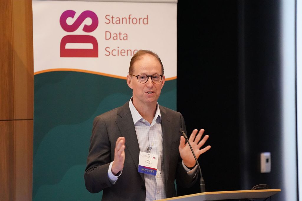 Russell Poldrack gestures while presenting at a Stanford Data Science 2026 CORES symposium, with a banner visible in the background.