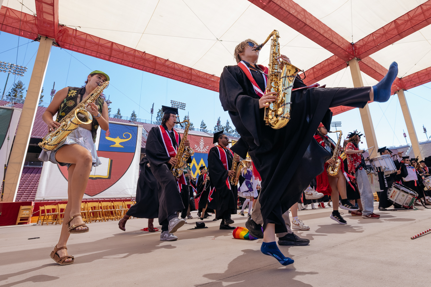 Band, including graduates in caps and gowns, performs while dancing at conclusion of commencement celebration.