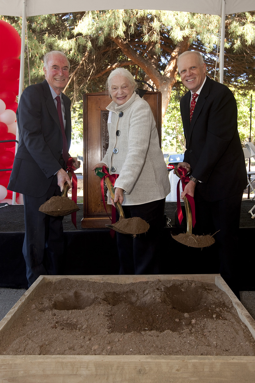 Peter and Helen Bing and John Hennessy under a tent holding ceremonial shovels at groundbreaking for Bing Concert Hall.