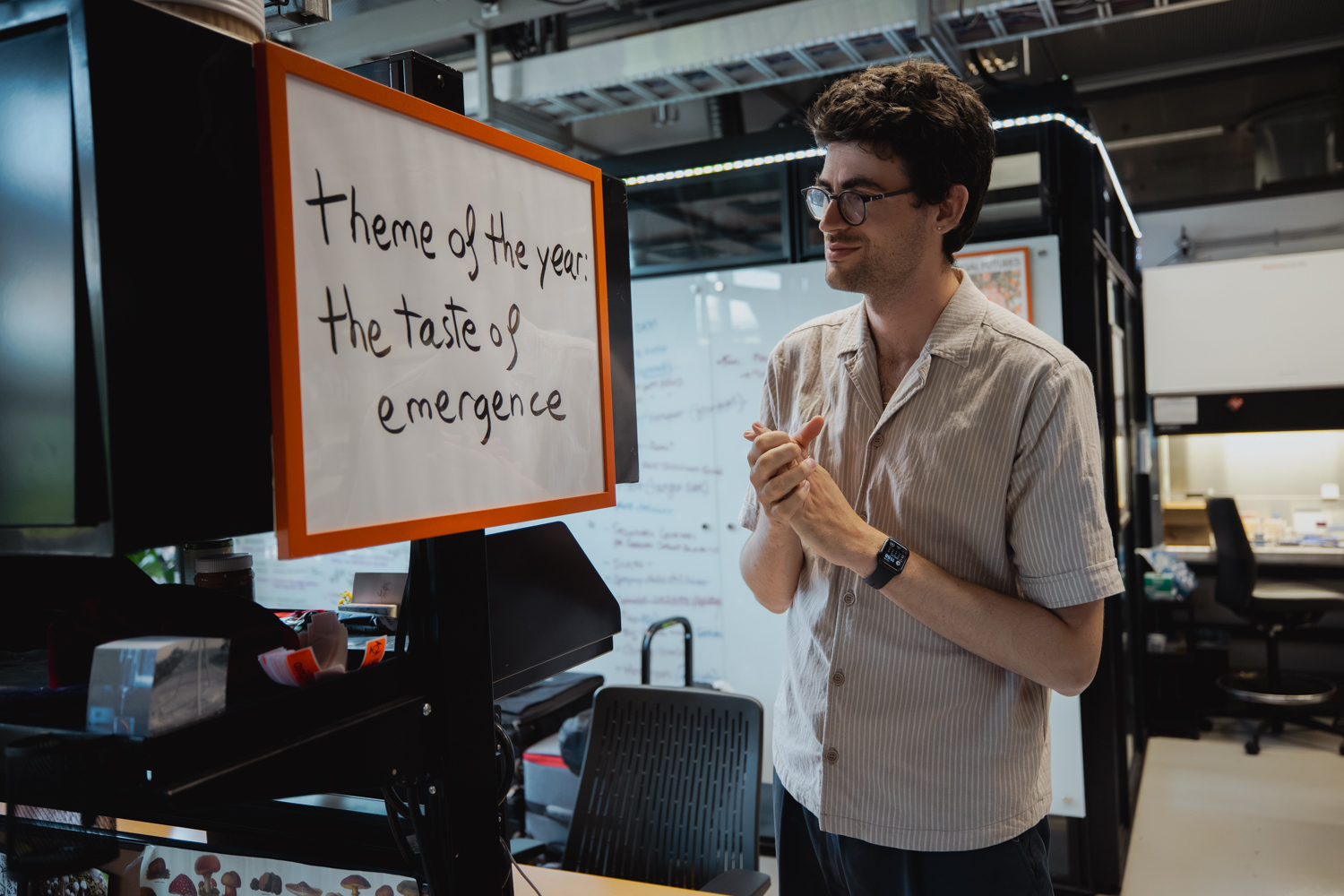 Vayu Hill-Maini stands reading a handwritten sign in the lab that states the group's theme for the year.