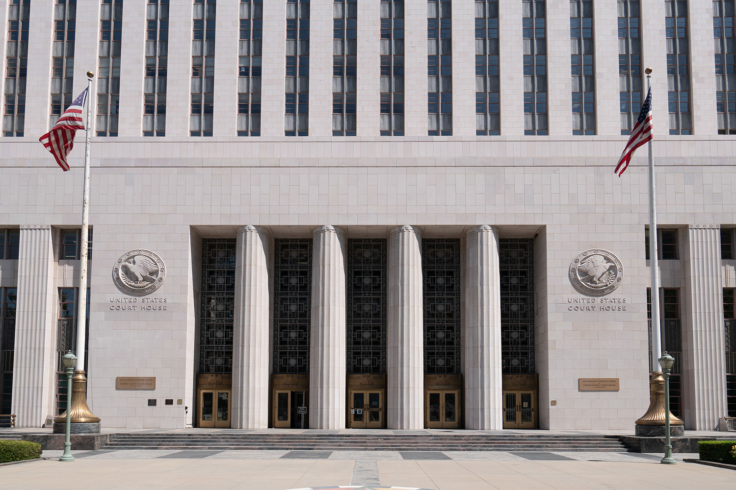 Art Deco federal courthouse entrance with tall columns and two American flags.