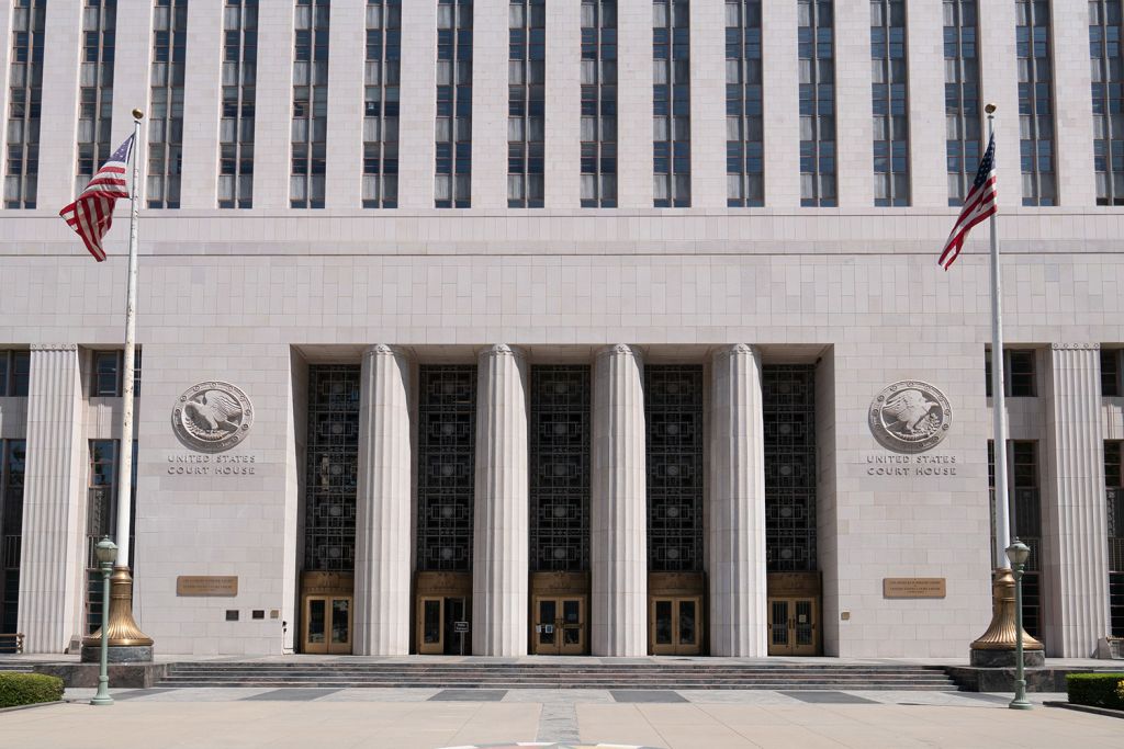 Art Deco federal courthouse entrance with tall columns and two American flags.