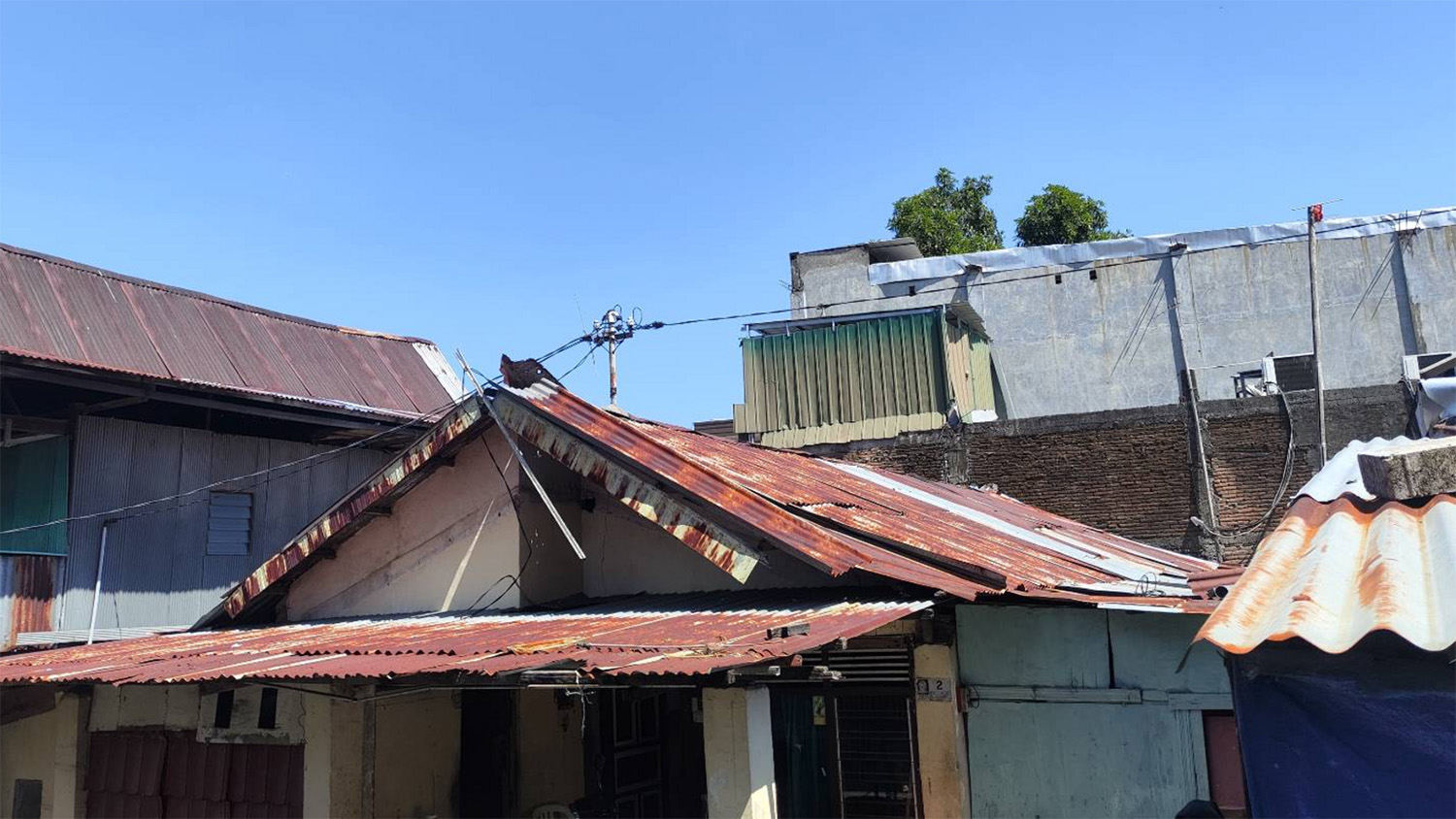 A row of buildings with rusted tin roofs in a residential area.