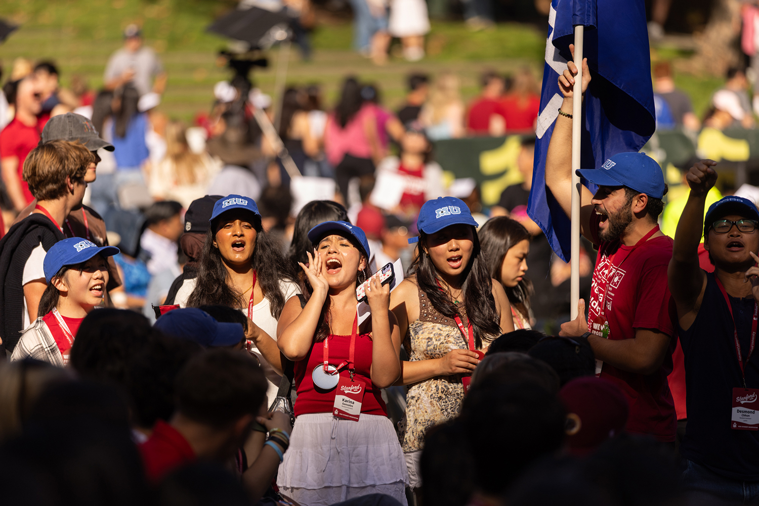 Students wave a blue flag and cheer together in a crowd.