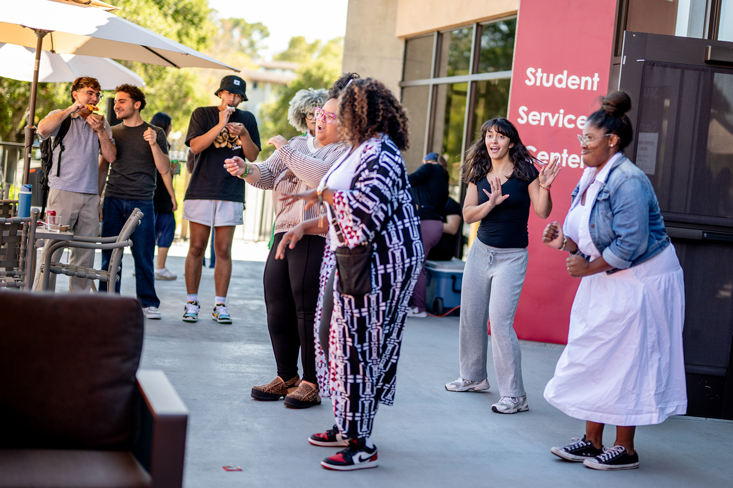 Students dance together outside the Student Services Center during a campus gathering.