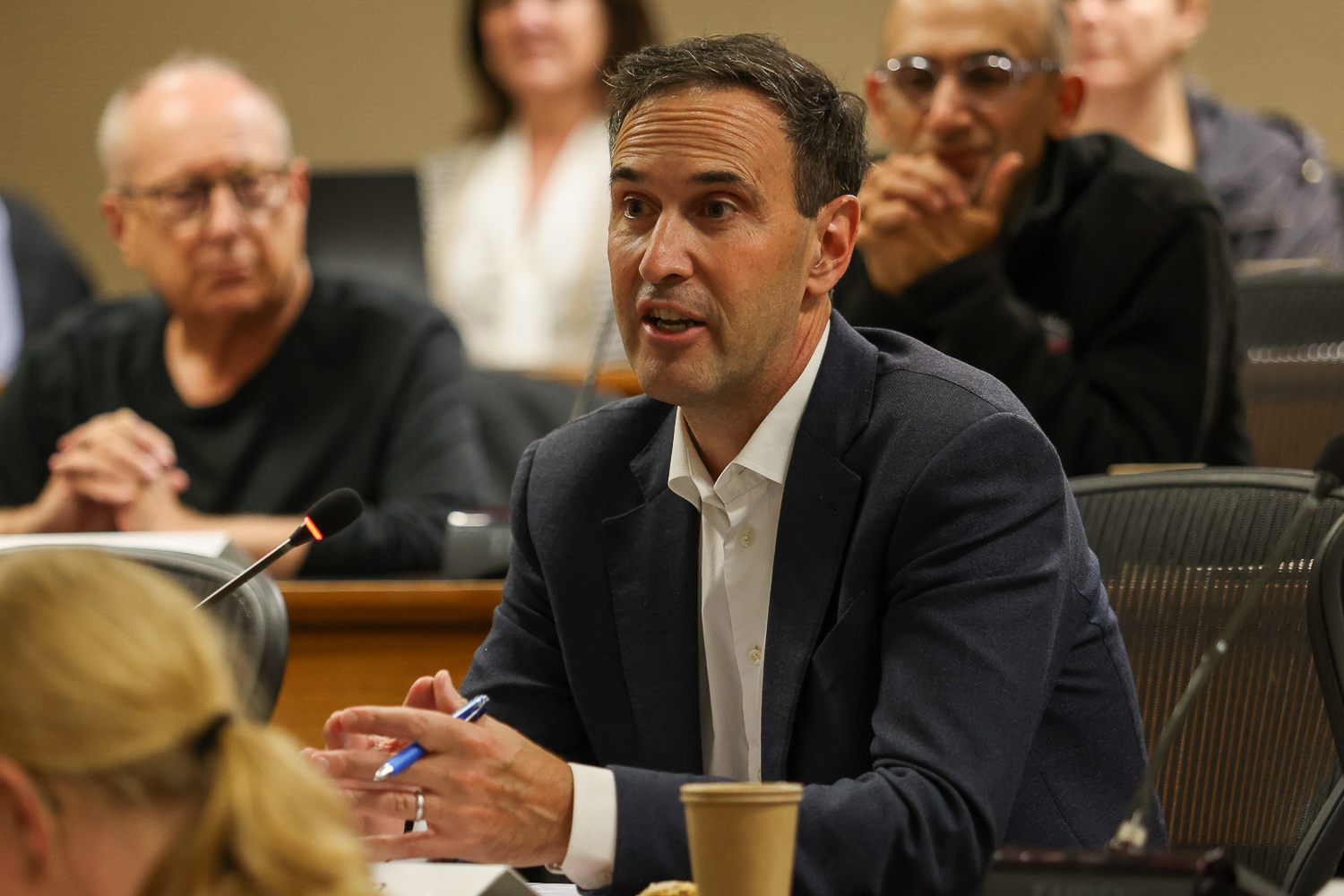 Stanford President Jonathan Levin sits with his hands clasped while addressing the Faculty Senate