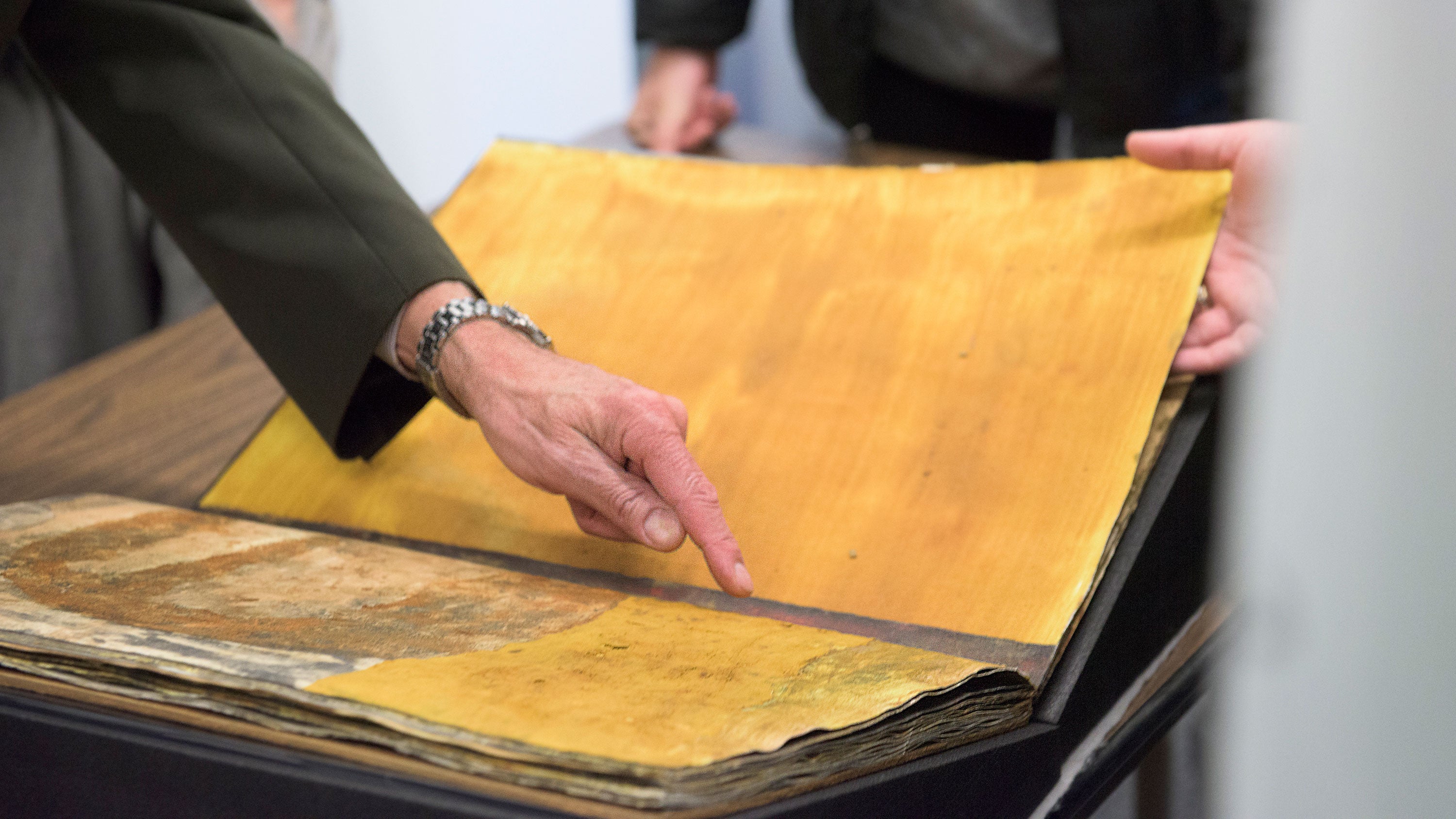 A close-up of two pages in Mars, showing a male librarian's forearm and hand, with his index finger pointing out the artwork's texture and markings (Image credit: L.A. Cicero)