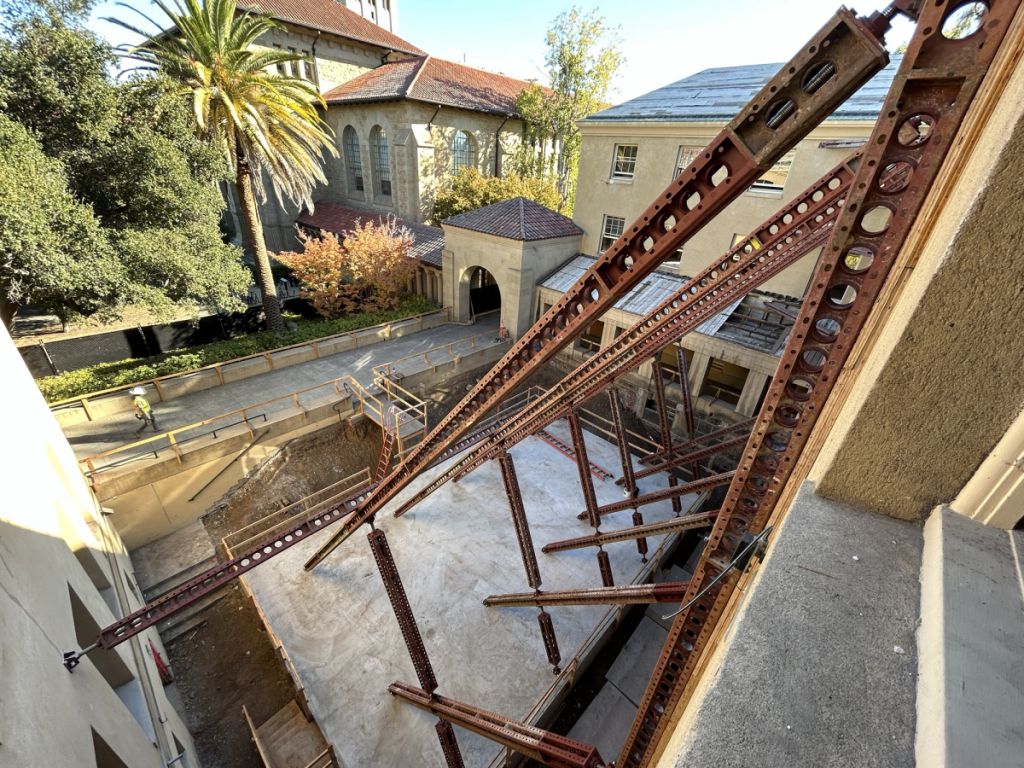 An above-ground view of construction, with rebar in the foreground and a palm tree in the background.