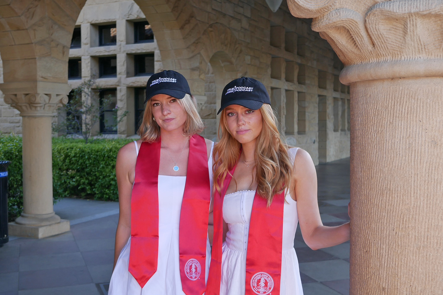 Grace Carroll and Kyleigh McPeek pose for a photo at Stanford while wearing their the True Crime Podcast Podcast hats.