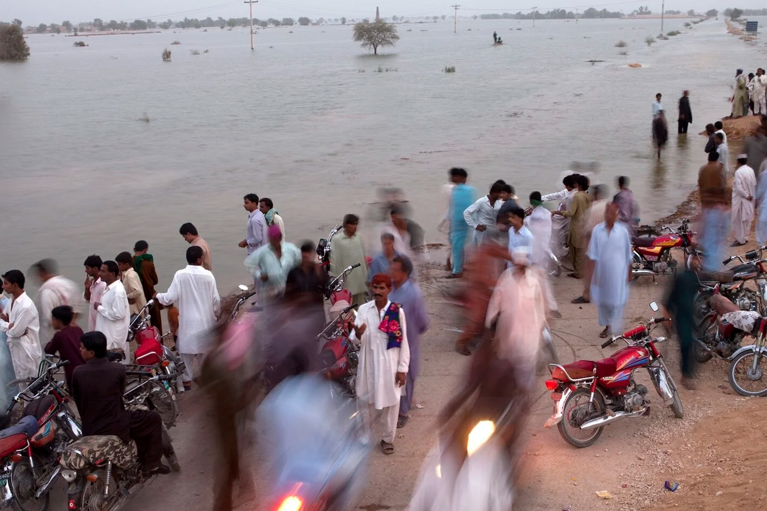 Image of local residents near Bhan, Pakistan, gathering to watch floodwaters slowly rise to block the Indus Highway.
