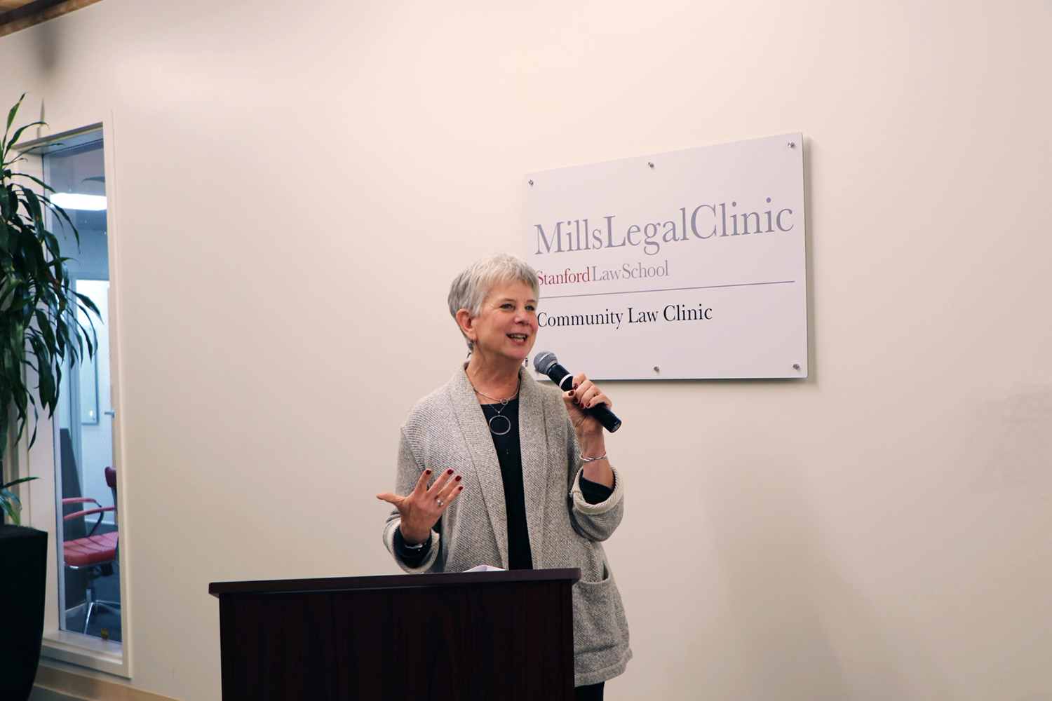 Image of Juliet Brodie speaking into a microphone at the new Community Law Clinic location.