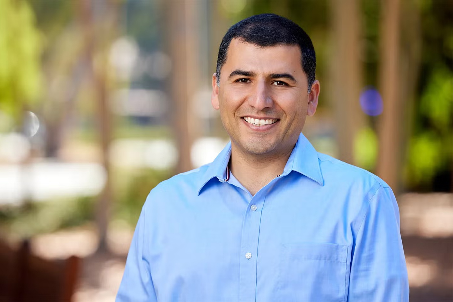 Open video Mohsen Bayati in a light blue shirt stands outdoors against a blurred green background, smiling and posing for the photo. in a modal