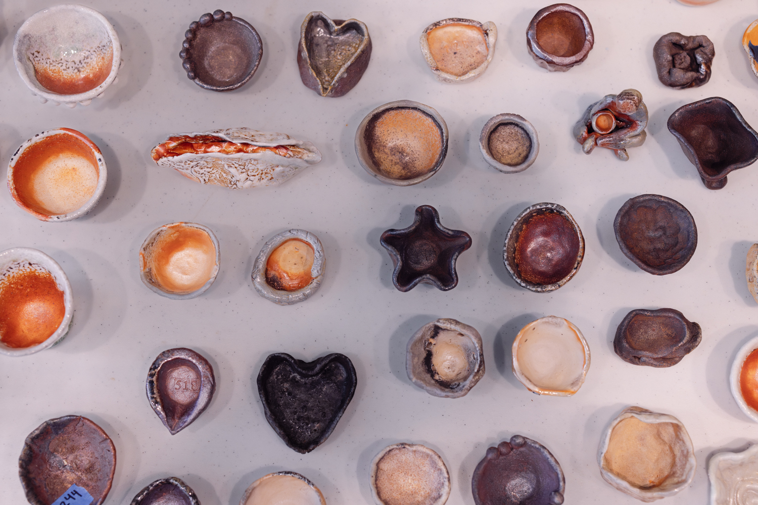 Collection of handmade ceramic bowls in various shapes, sizes, and glazes arranged on a white surface.