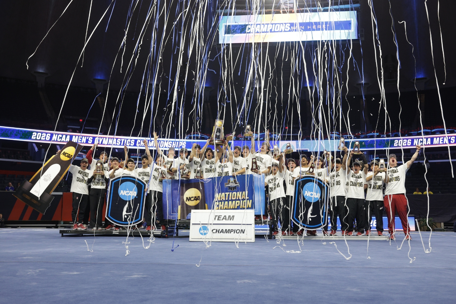 The men's gymnastics team poses for a photo while celebrating their NCAA Championship win.