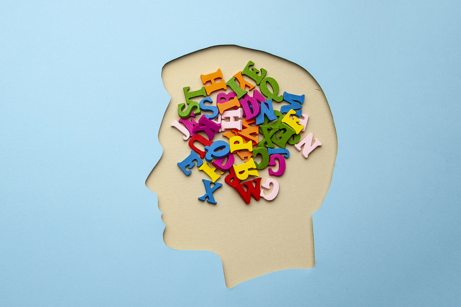 Illustration of colorful letters filling a paper head silhouette, symbolizing language and thought.
