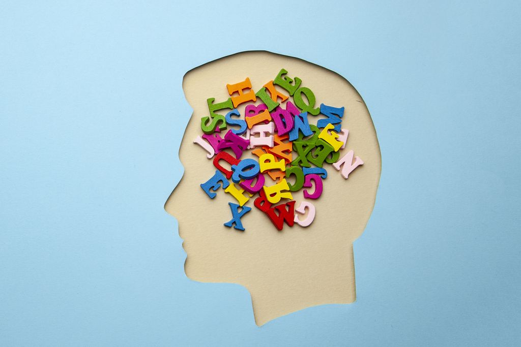 Illustration of colorful letters filling a paper head silhouette, symbolizing language and thought.