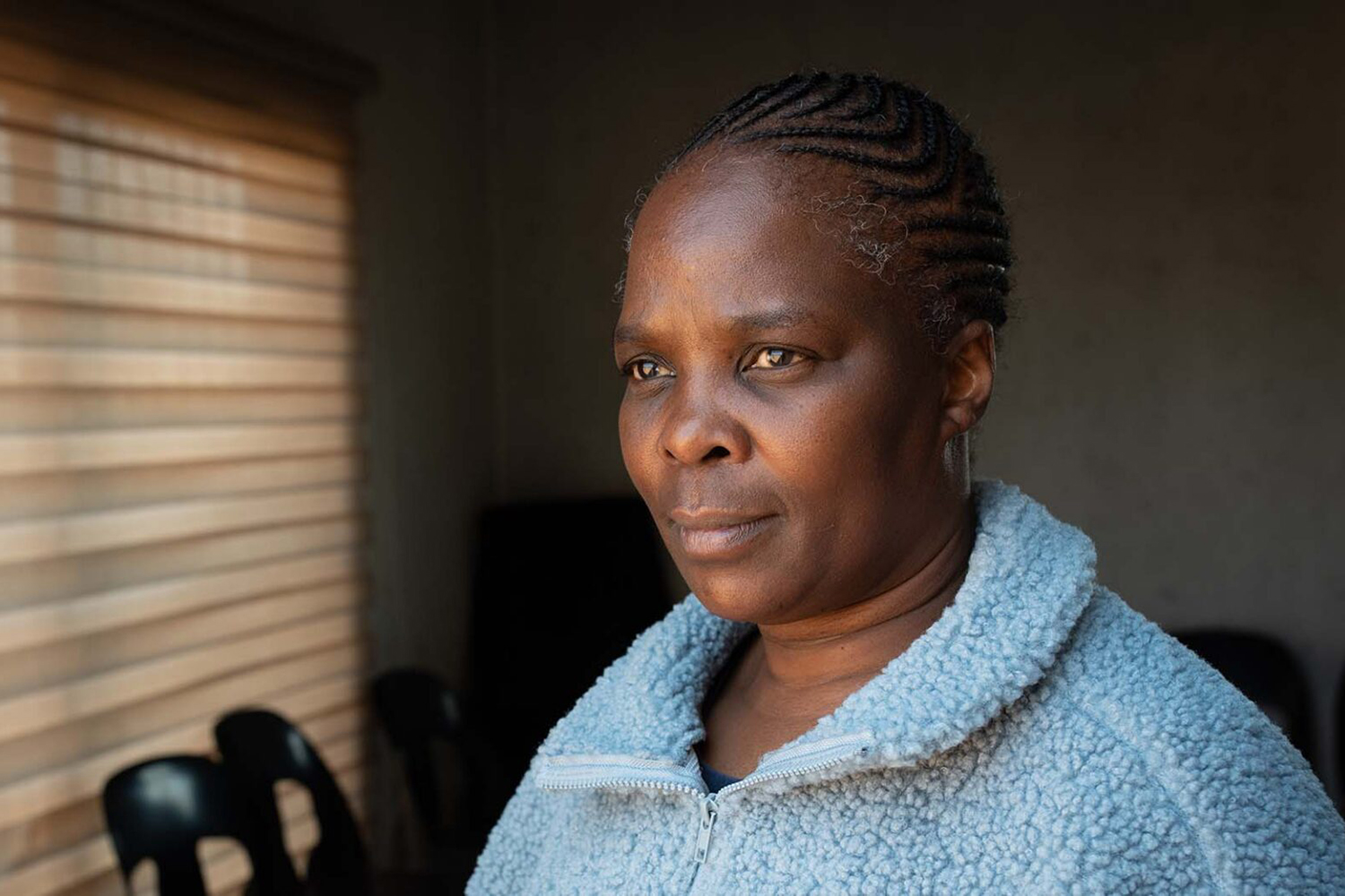 Promise Mabilo, posing for a photo, looks out a window in soft light.