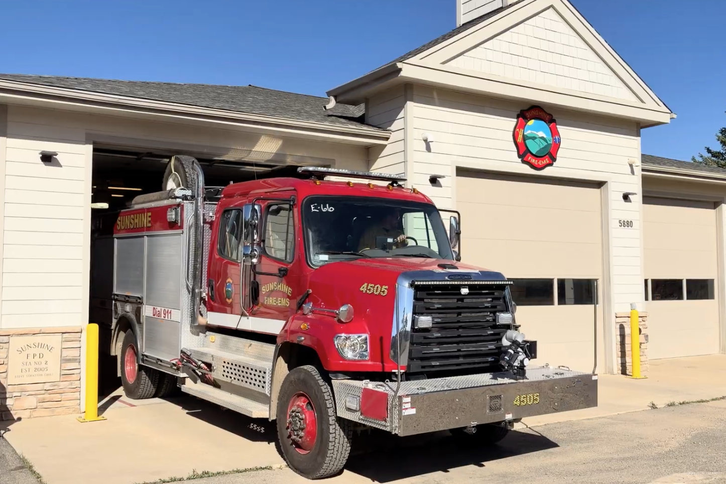 Red Sunshine Fire-EMS engine 4505 pulling out of a fire station bay under clear blue sky.