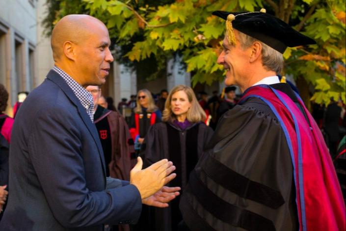 Corey Booker speaking as Marc Tessier-Lavigne listens.