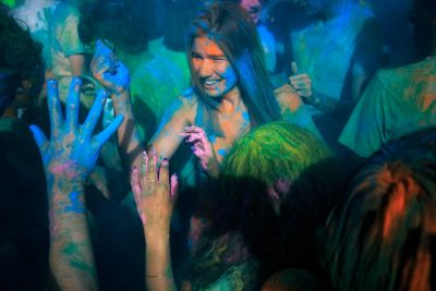 Student covered in colored dust, smiling.