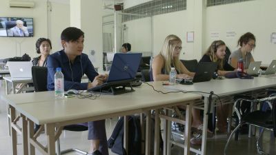 people working on laptops as they observe a televised trial