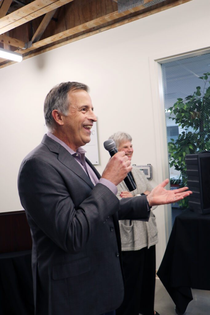 Image of George Triantis speaking into a microphone at the new Community Law Clinic location.