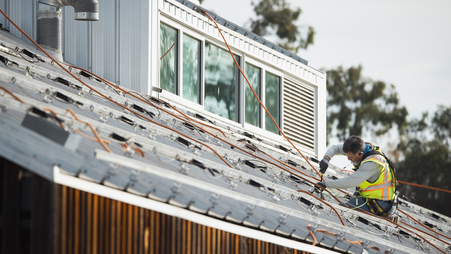 Image of a person installing the foundation for solar panels on the roof of the O'Donohue Family Stanford Educational Farm.