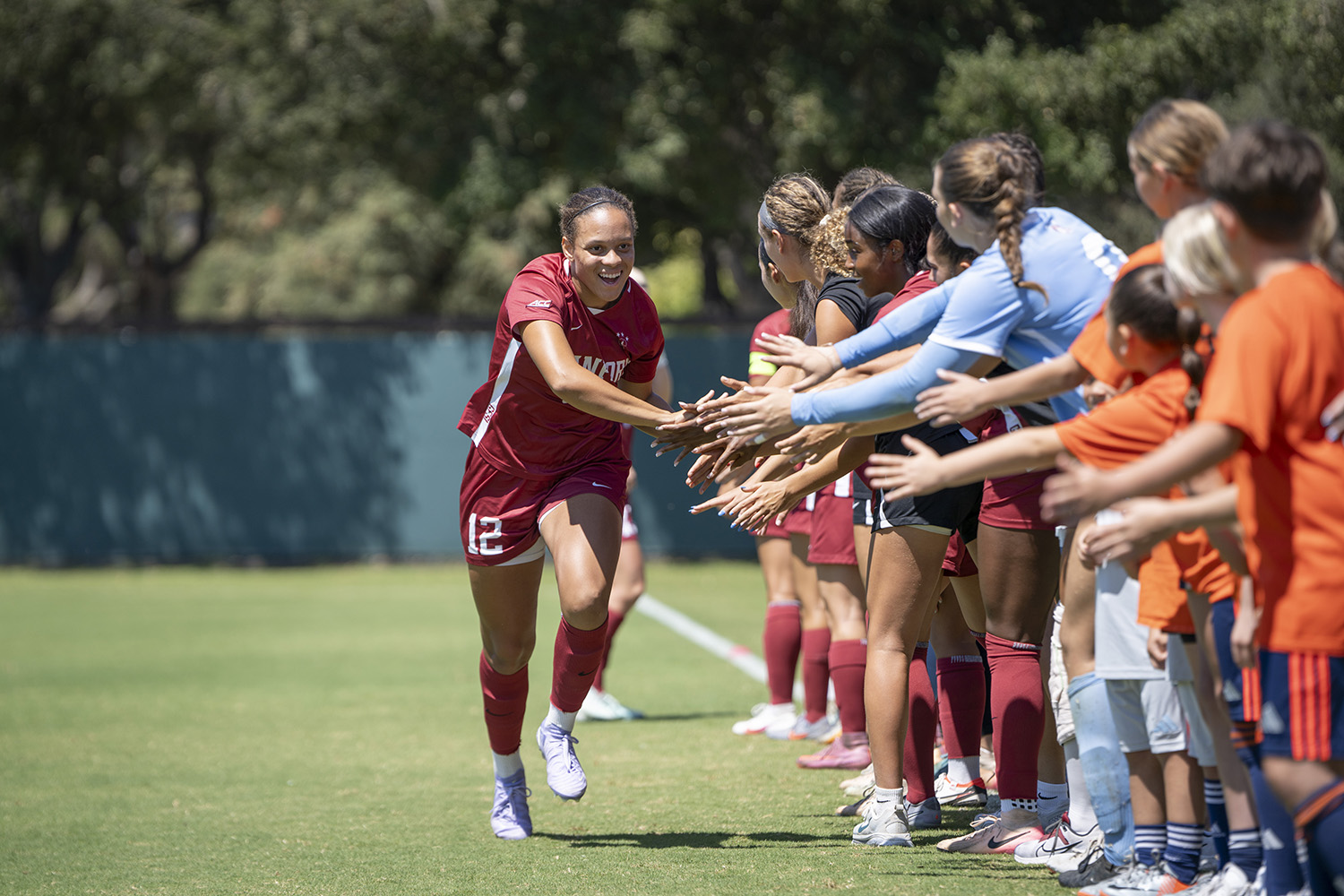 Jasmine Aikey slaps hands with spectators at the sideline.
