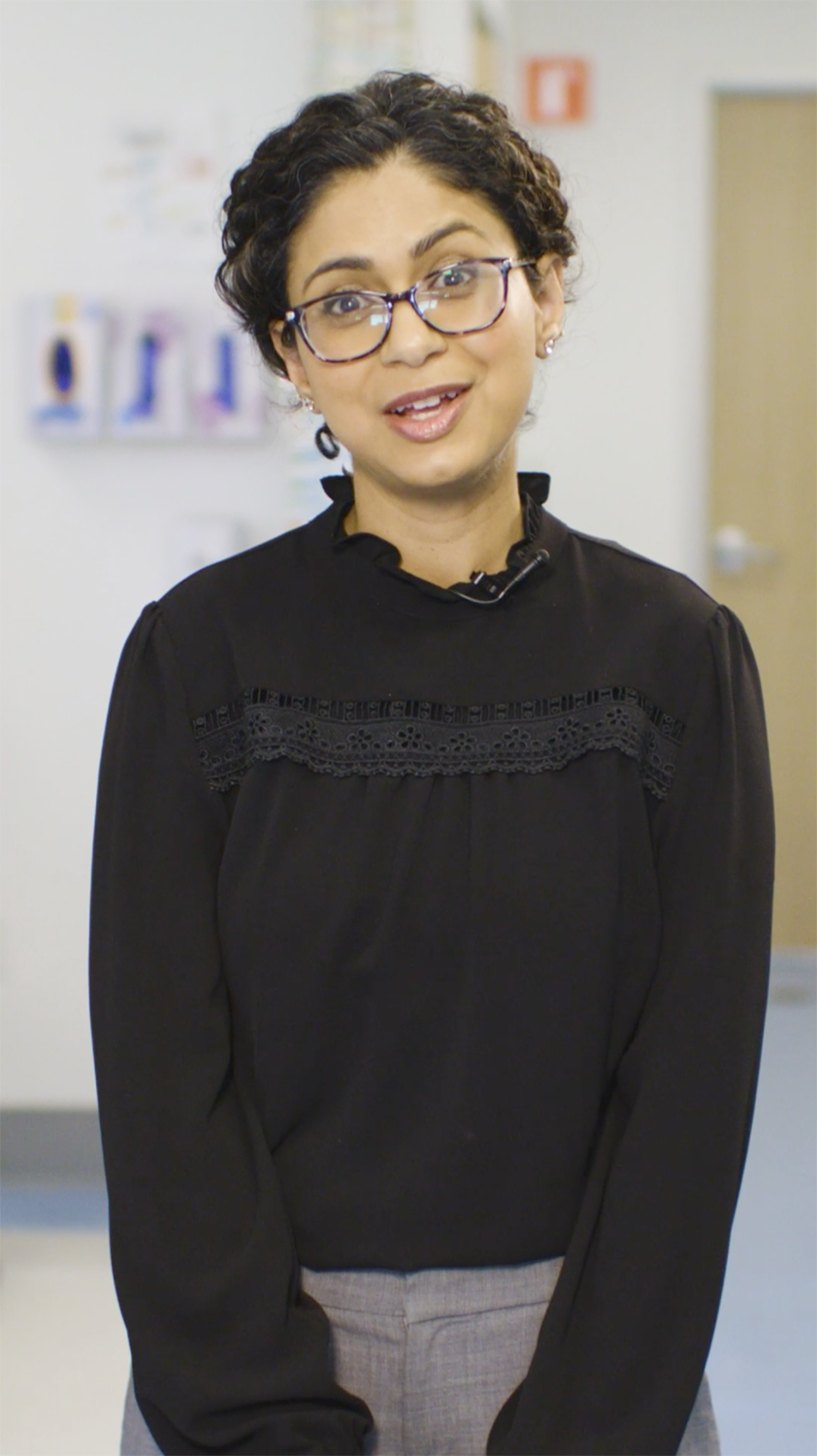 Tina Sindher standing and speaking to a camera during an interview.