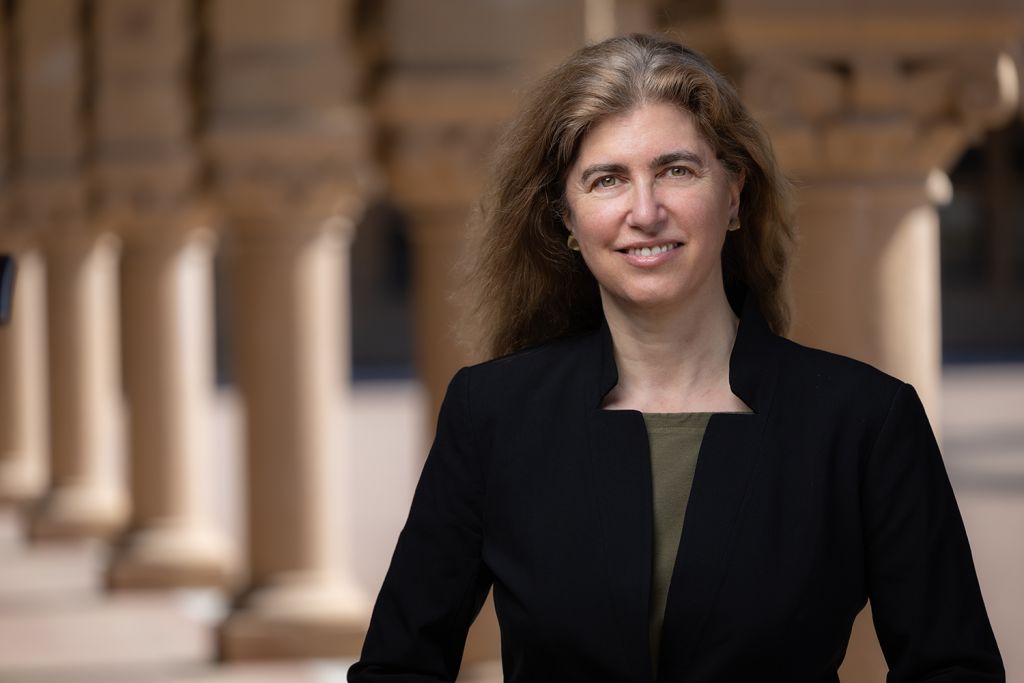 Jessica Riskin in black blazer smiling in the Stanford Quad arcade.