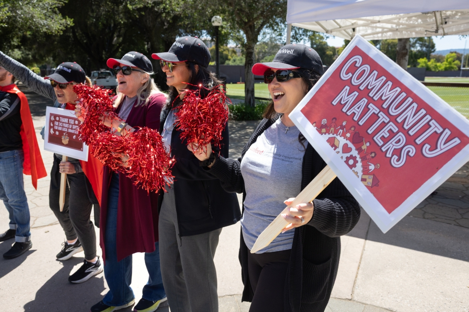 Participants holding pom-poms and signs promoting community engagement, showing enthusiasm for a positive cause during an outdoor event.