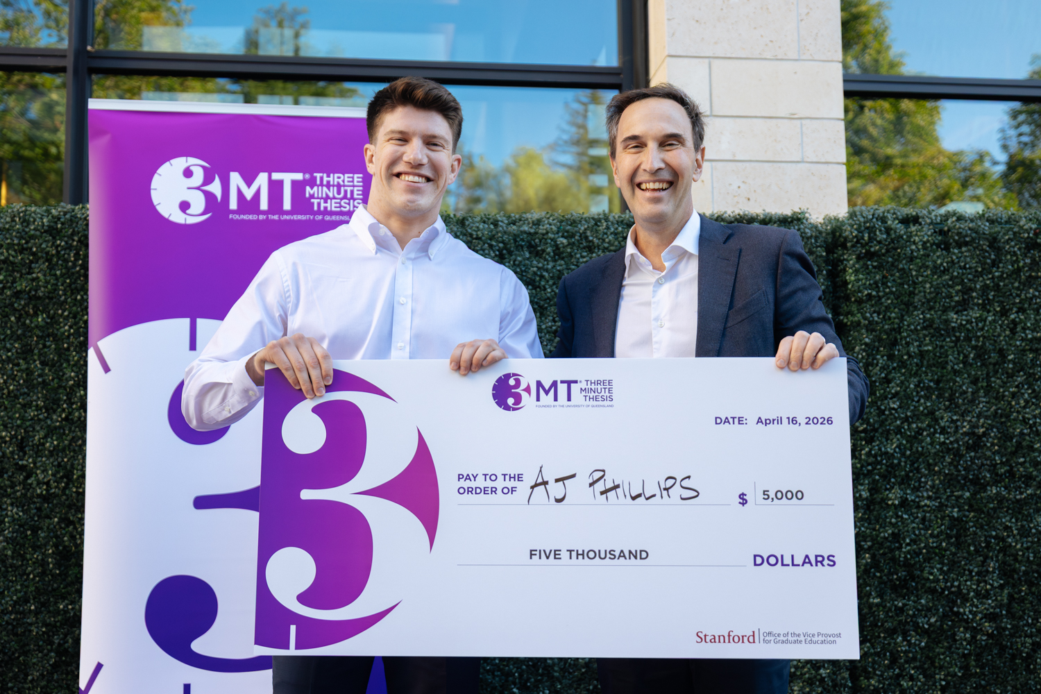 Winner AJ Phillips with President Levin holding a large ceremonial check for $5,000 from the Three Minute Thesis competition.
