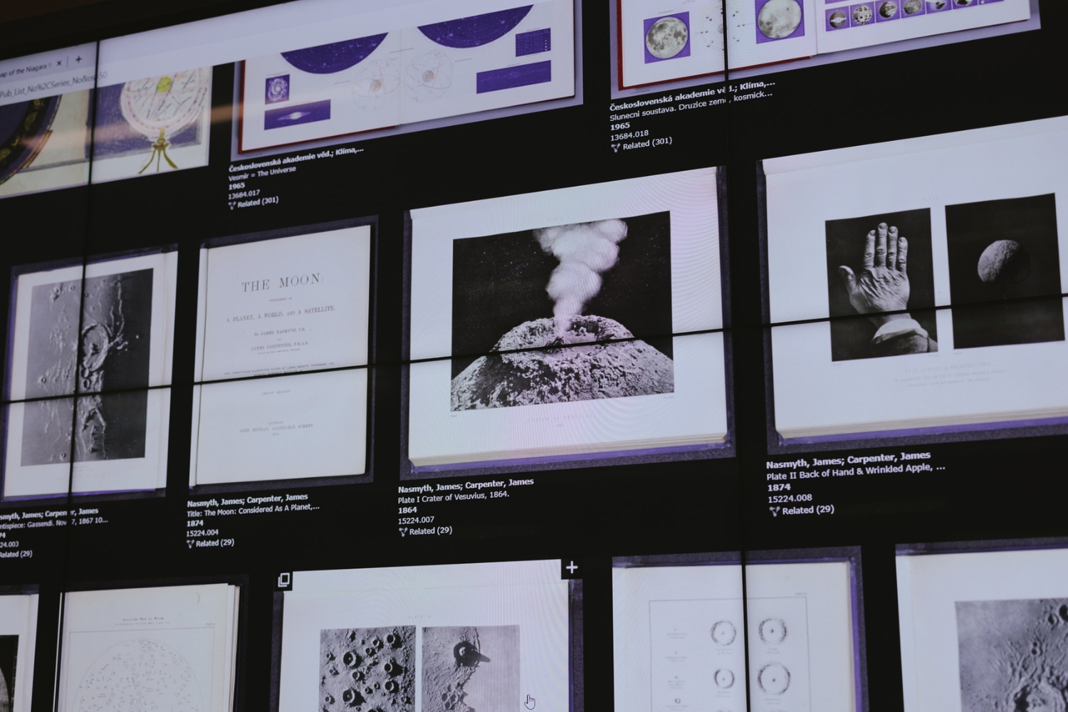 A digital display shows various historical lunar and volcanic images, including photographs and publications about the moon and celestial observations.