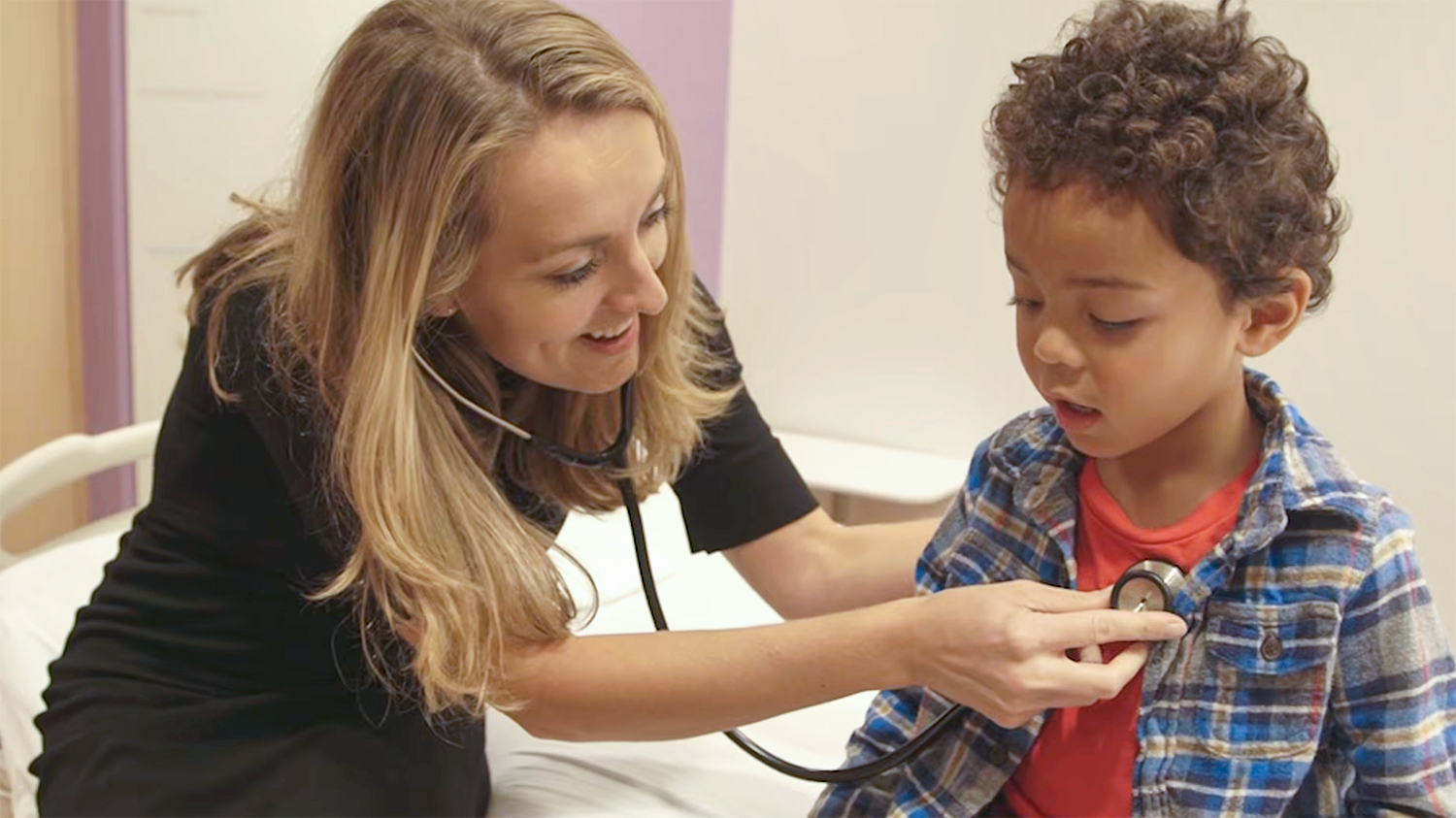 A doctor checks a child's heartbeat with a stethoscope in a medical office.
