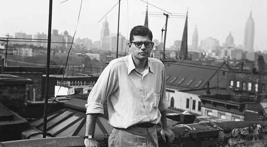 Young Allen Ginsberg stands on a rooftop with a skyline view of buildings, including the Empire State Building.
