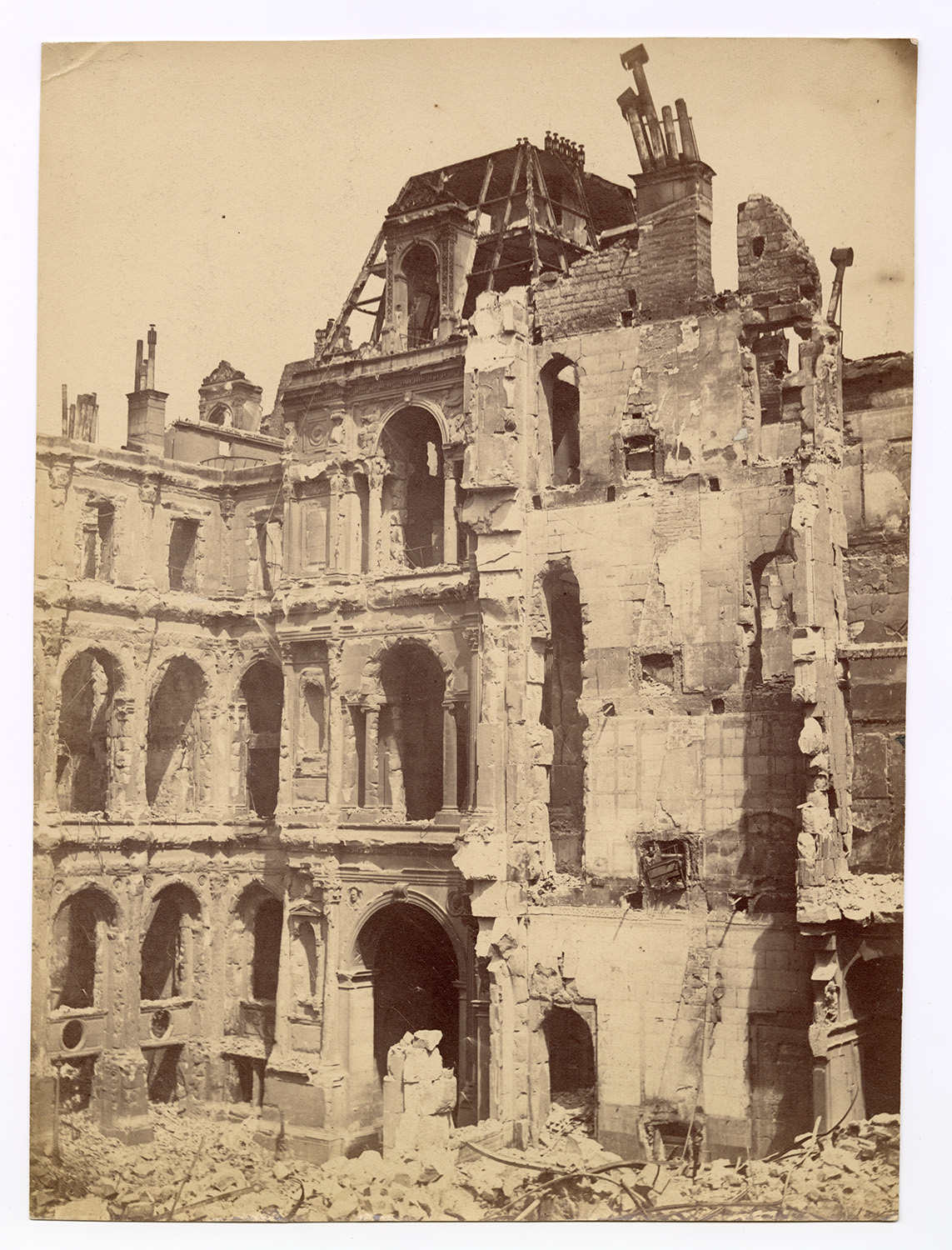 A historic photograph shows the Hôtel de Ville in ruins, its ornate facade gutted by fire.
